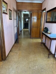 Vista de un pasillo interior con paredes de color rosa y muebles de madera.