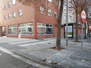 Fachada de una academia de inglés con ventanas grandes y árboles cercanos.